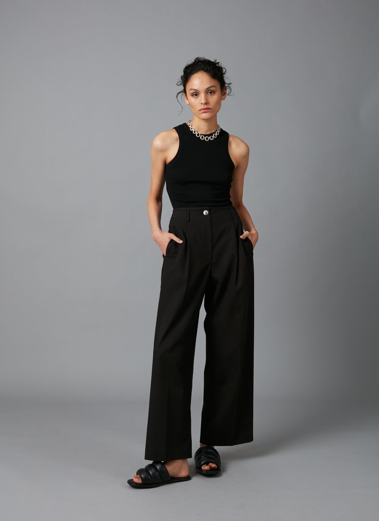 Front view of model with black tank and  Black Sculpture Cotton Tencel Pants
