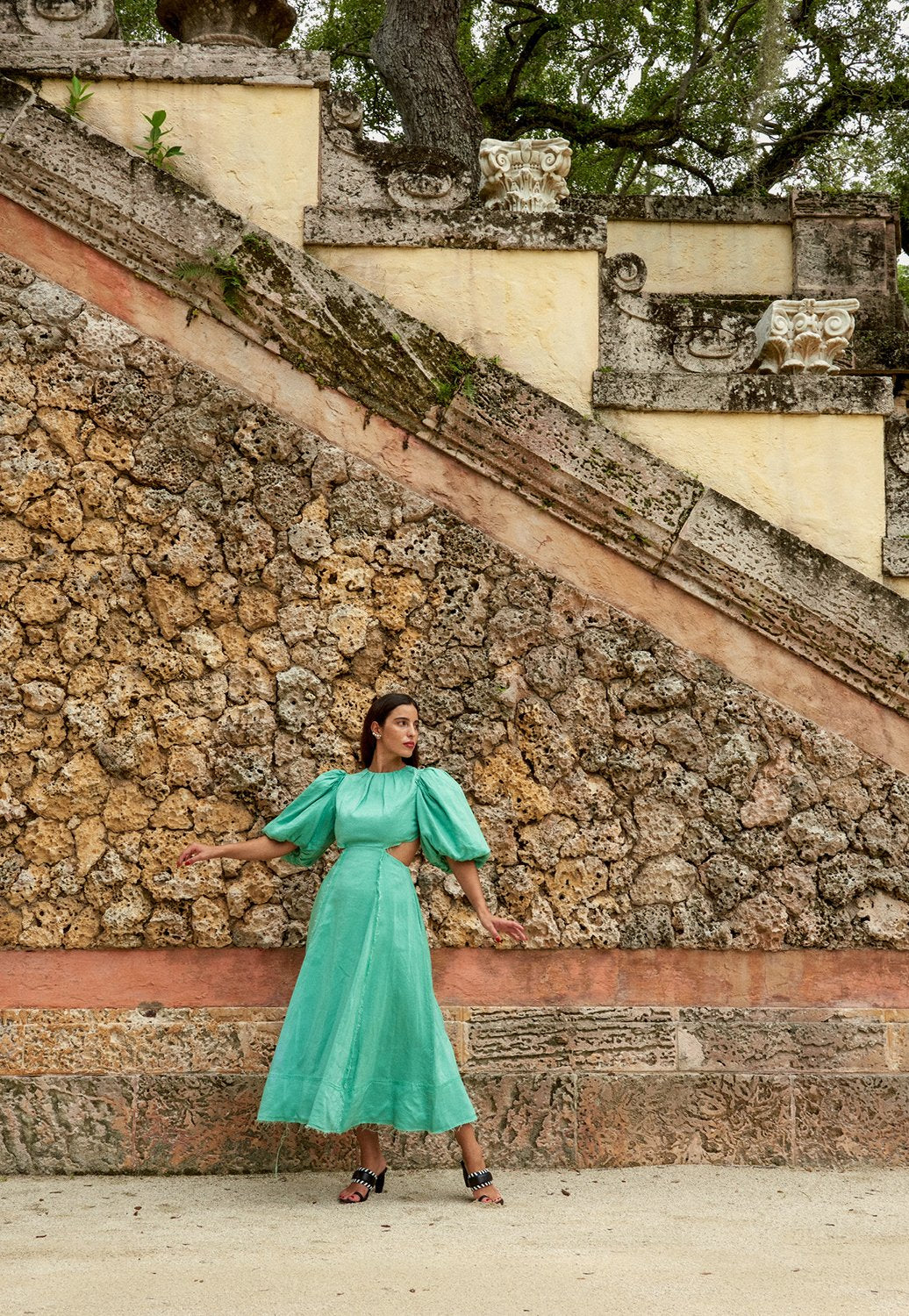 Model posing in front of rock wall in green dress