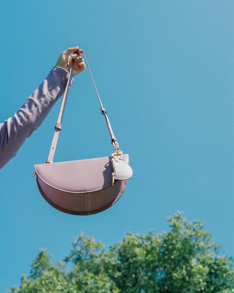 SIMÉTRIE - THICK CRESCENT MOON BAG - PURPLE Held up to the blue sky